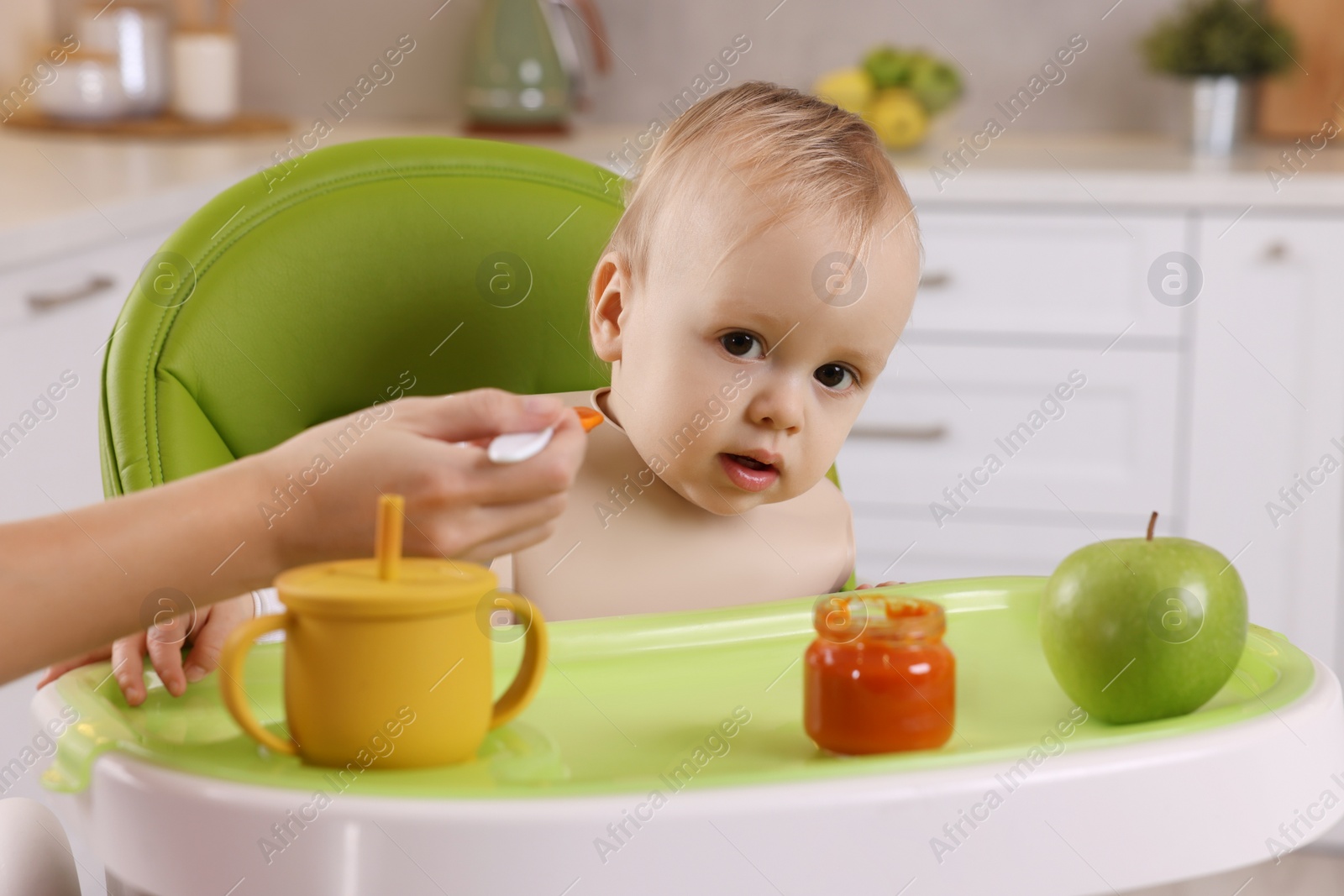 Photo of Mother feeding her cute little baby with healthy food at home