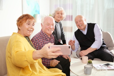 Elderly people taking selfie at table in living room