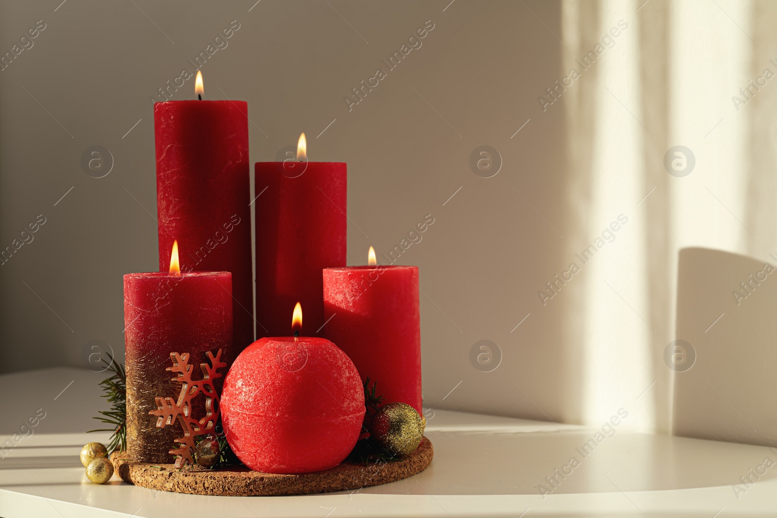 Photo of Burning candles with Christmas decor on white table. Space for text