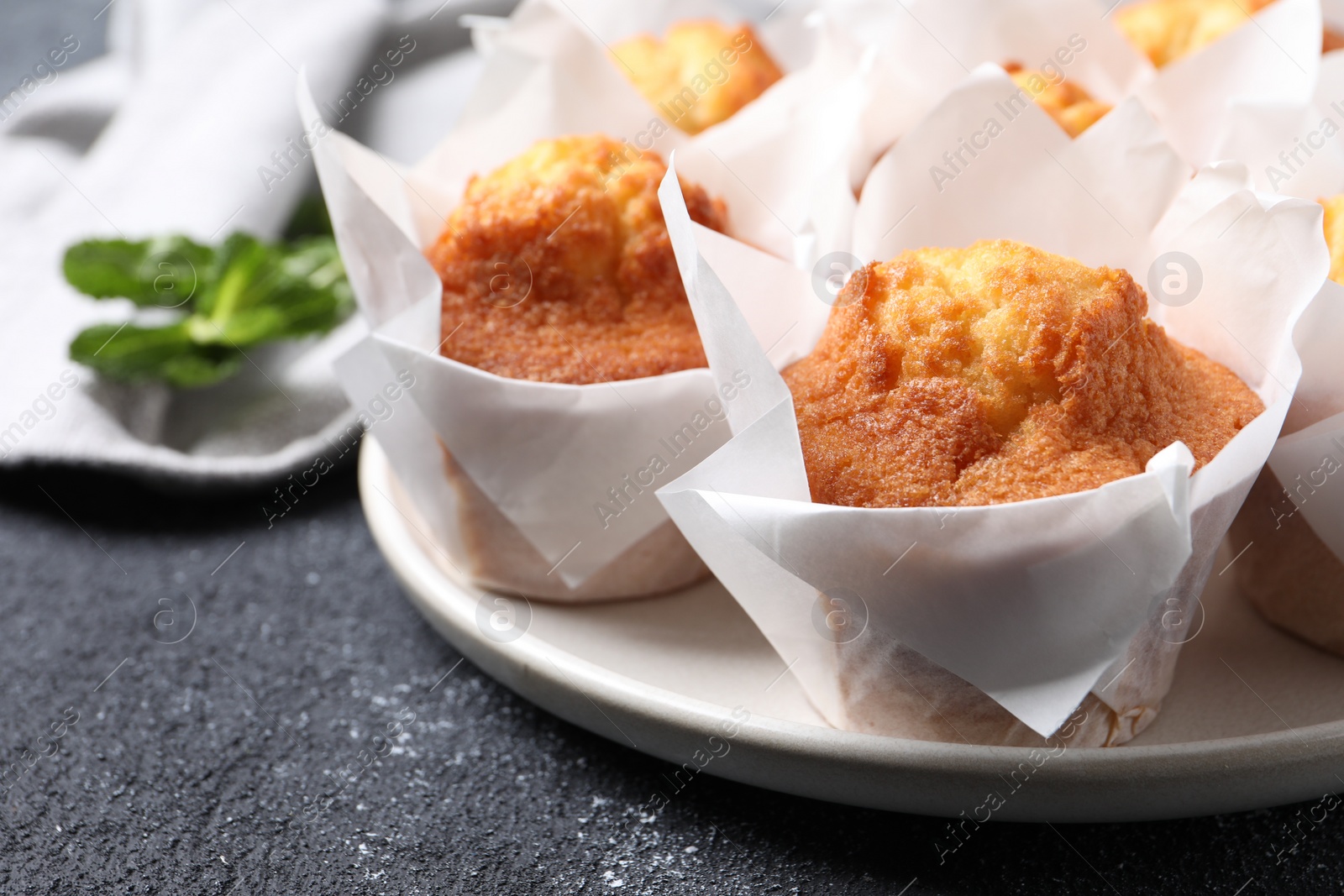 Photo of Delicious sweet muffins on black textured table, closeup. Space for text