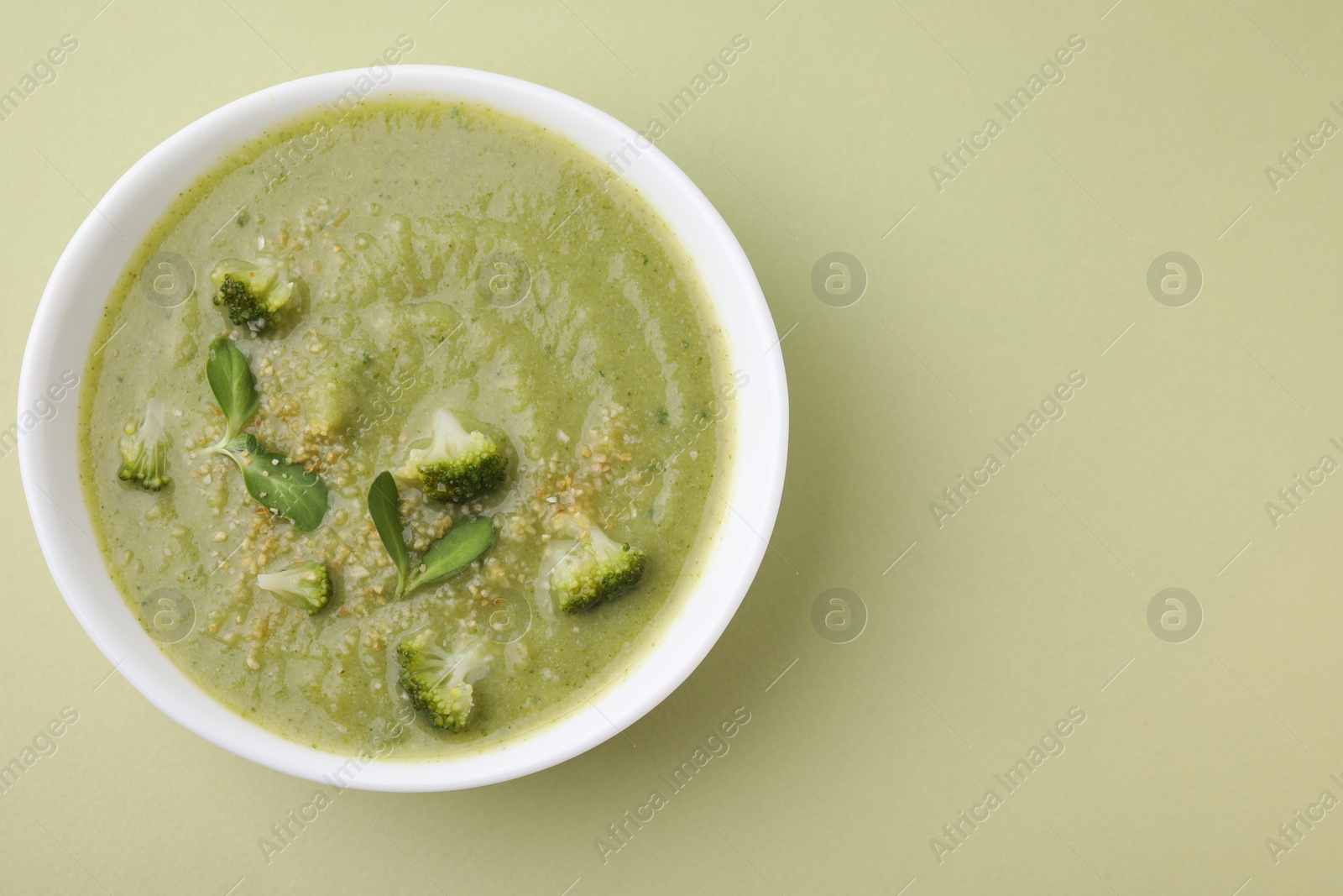 Photo of Delicious broccoli cream soup on olive background, top view. Space for text