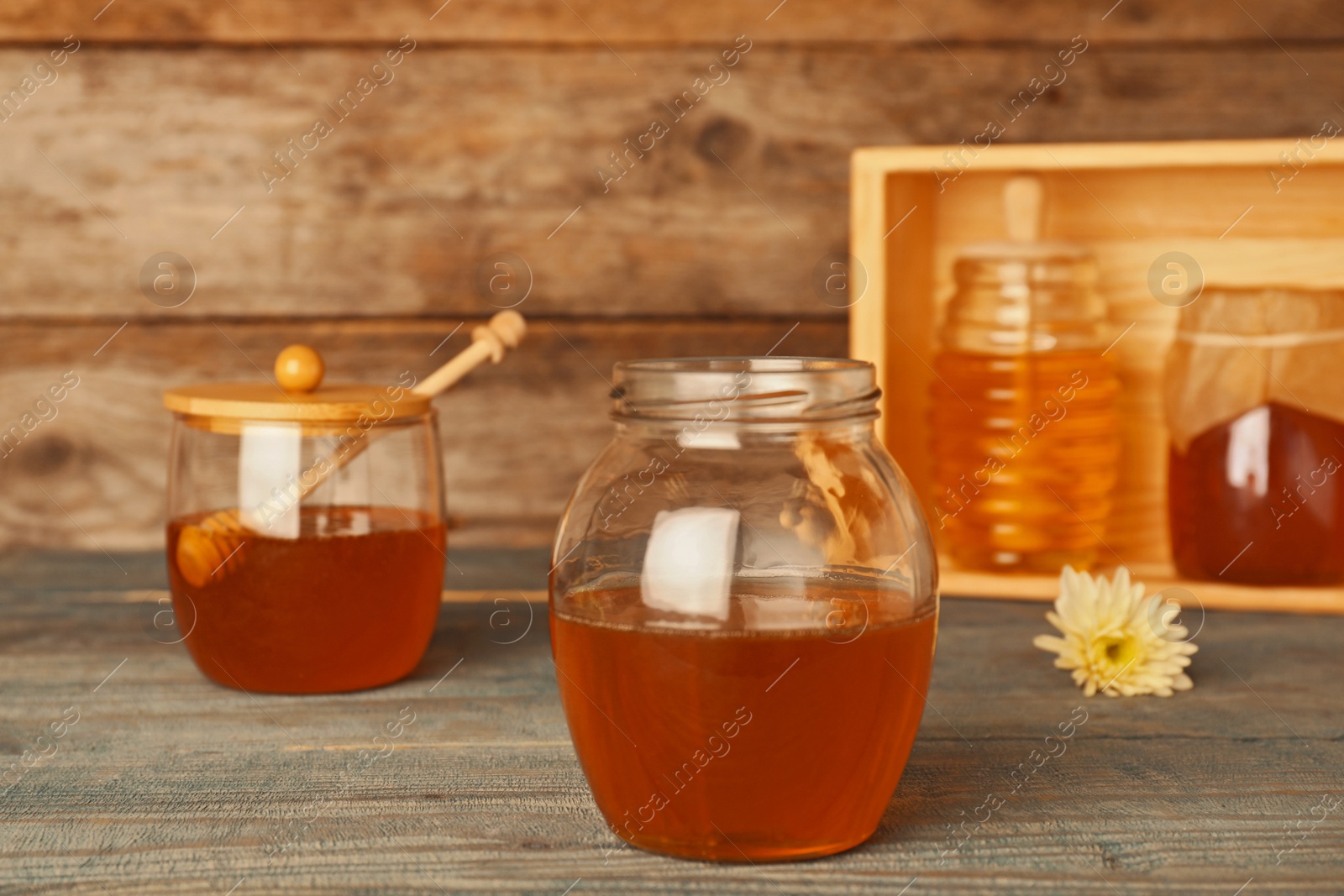 Photo of Glassware with tasty honey on wooden table