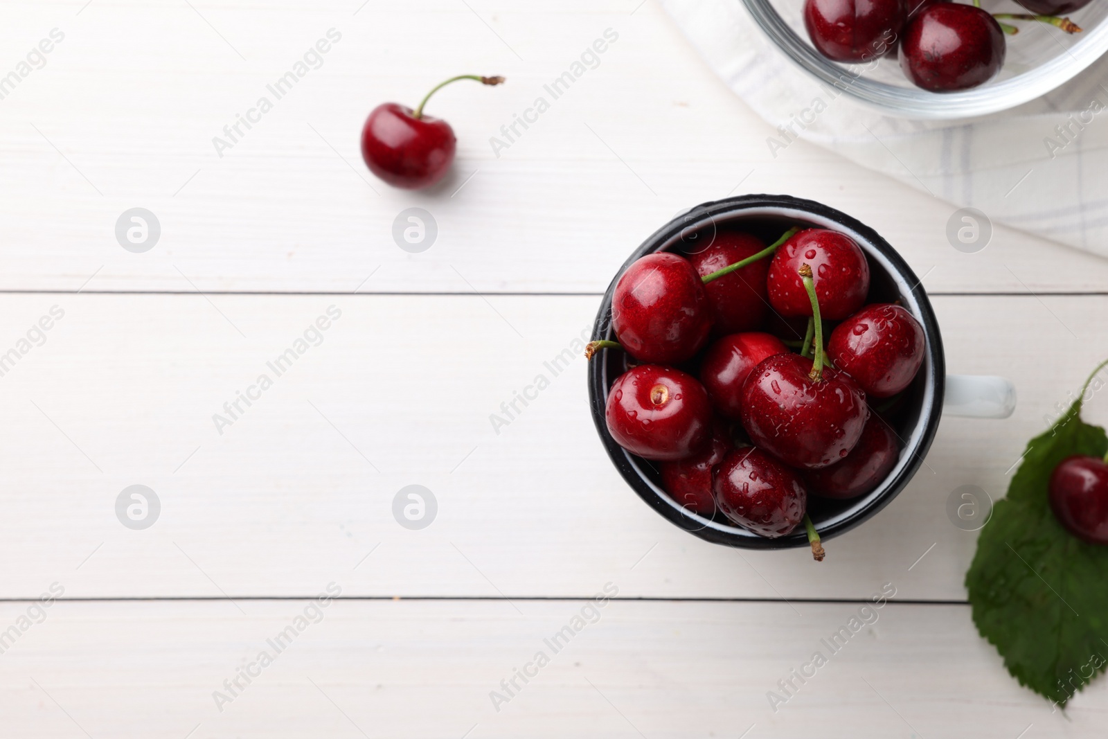 Photo of Fresh red ripe cherries with water drops on white wooden table, flat lay. Space for text