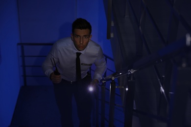 Male security guard with flashlight and portable radio transmitter in dark room