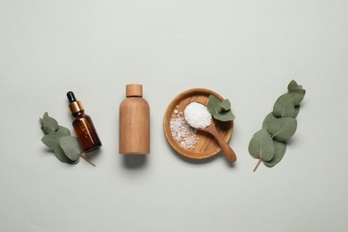 Photo of Aromatherapy products. Bottles of essential oil, sea salt and eucalyptus leaves on grey background, flat lay