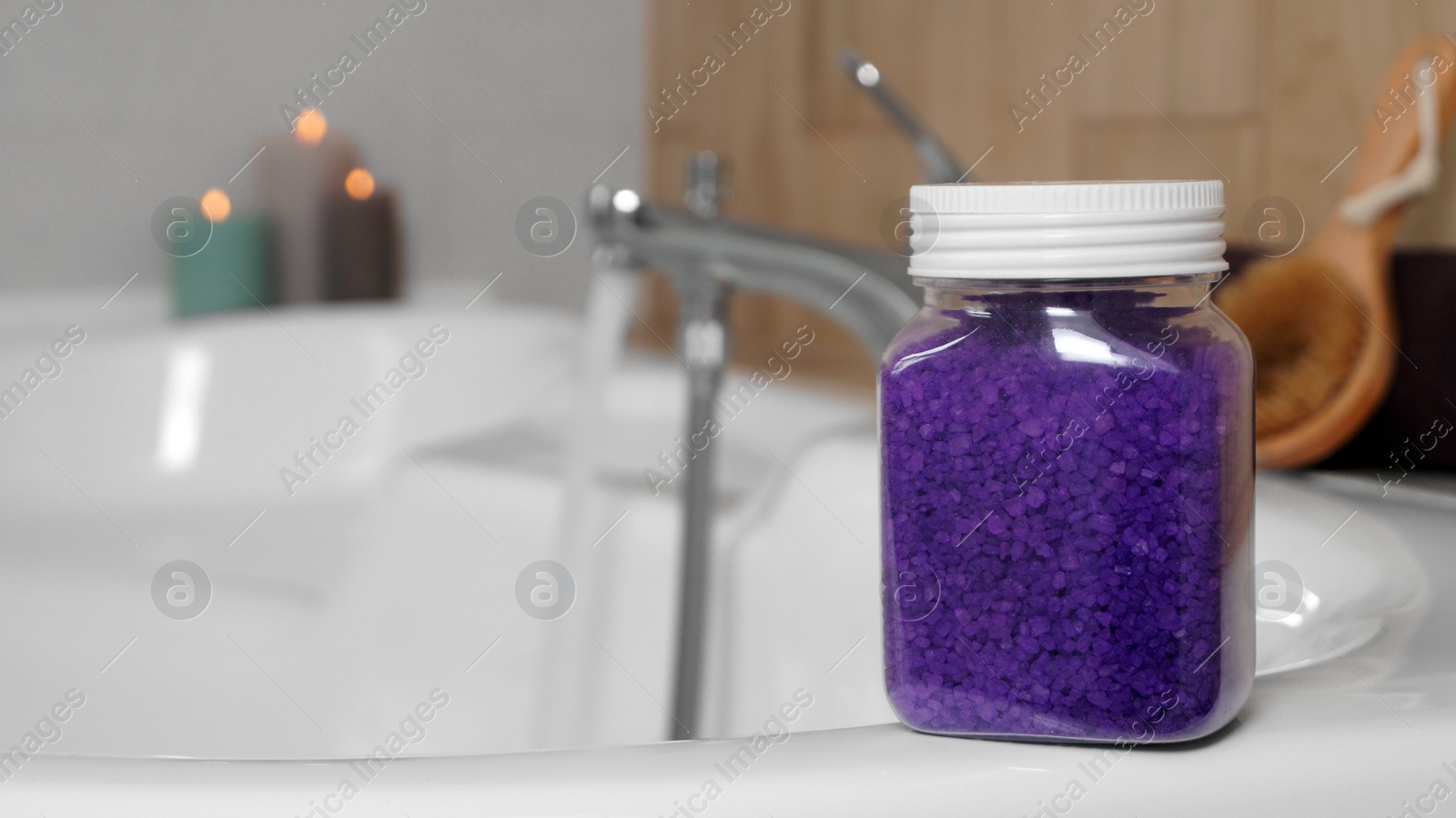 Photo of Jar with purple sea salt on bath. Space for text