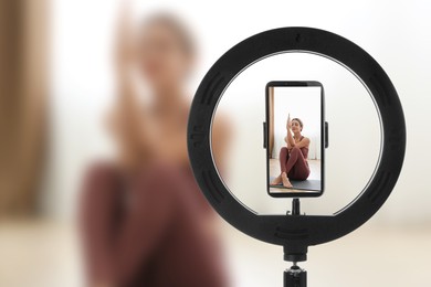 Young woman practicing yoga , selective focus on ring light and smartphone display