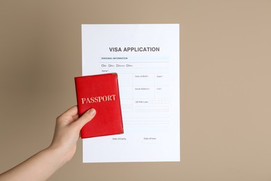 Woman holding visa application form for immigration and passport on beige background, closeup