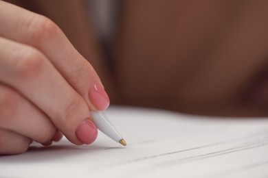Photo of Woman signing documents at table in office, closeup. Space for text