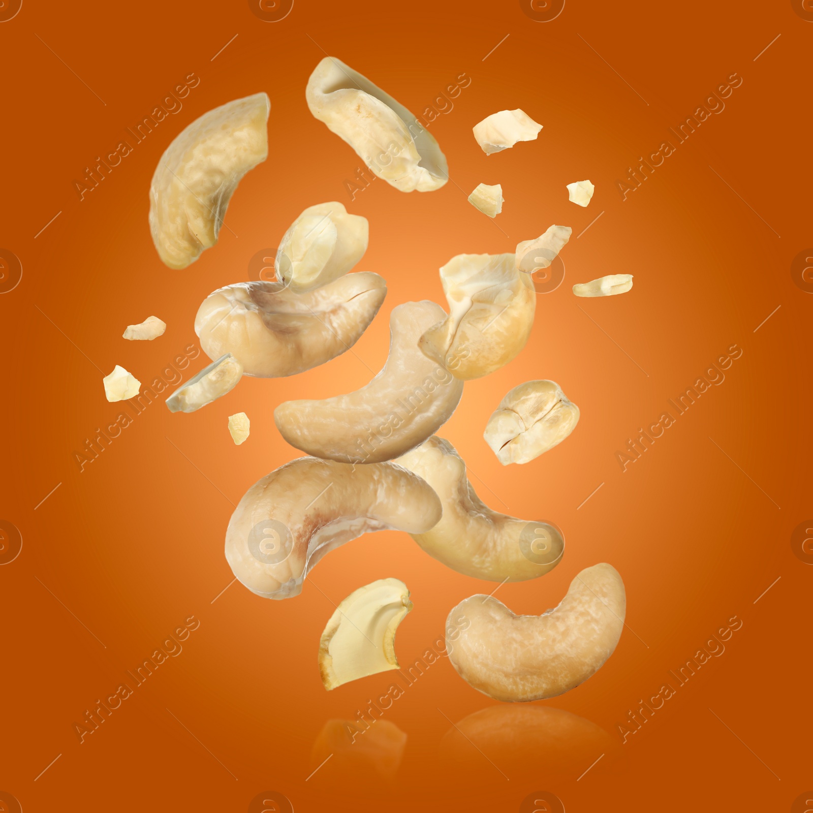 Image of Tasty cashew nuts flying on orange background