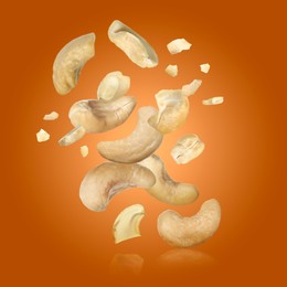 Image of Tasty cashew nuts flying on orange background