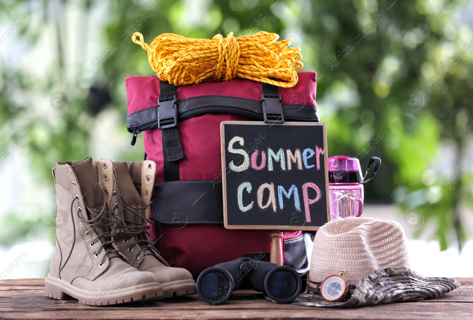 Photo of Composition with backpack and camping equipment on table against blurred background