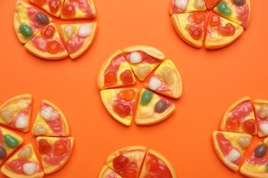 Delicious gummy pizza candies on orange background, flat lay