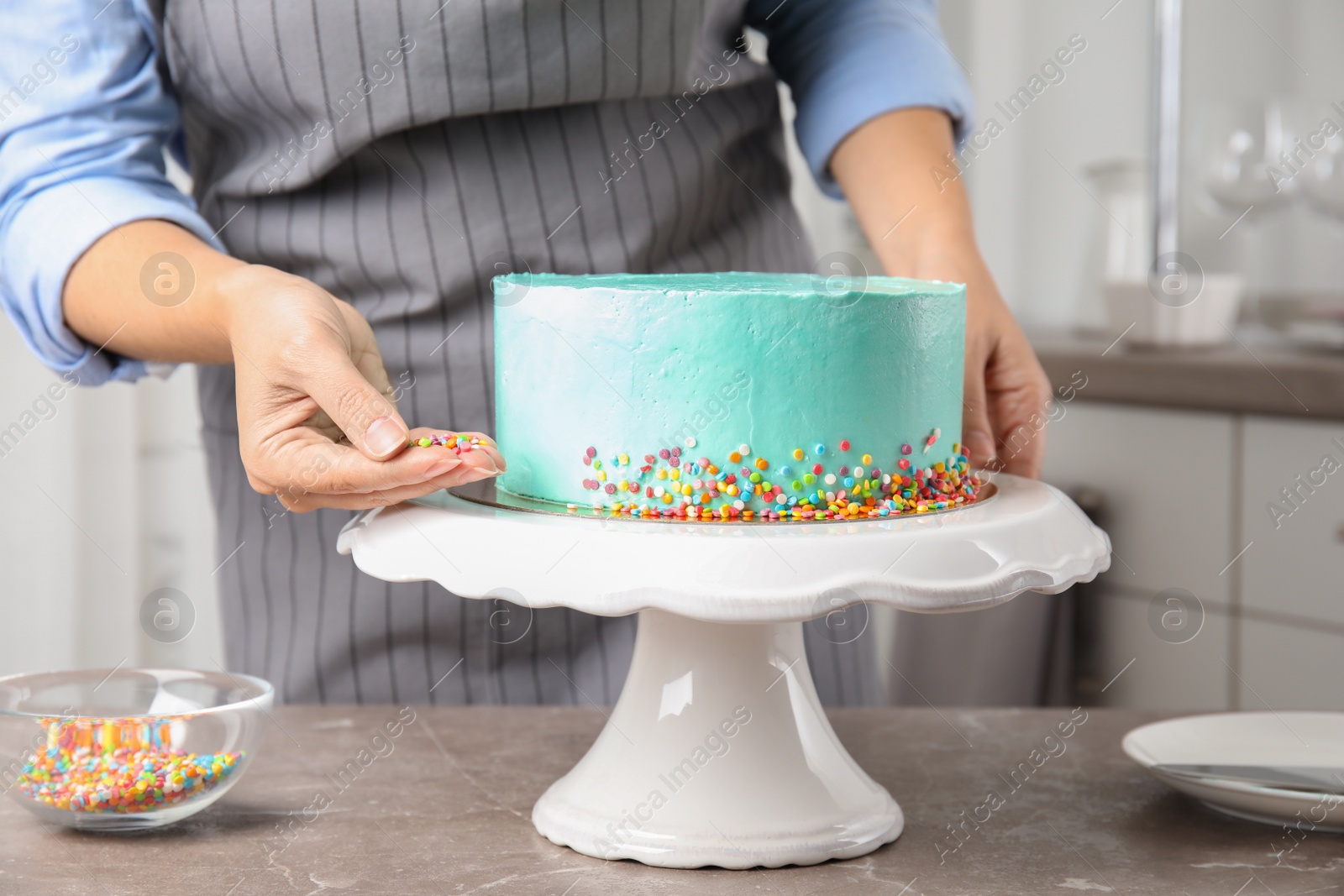 Photo of Woman decorating fresh delicious birthday cake in kitchen, closeup