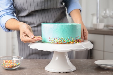 Woman decorating fresh delicious birthday cake in kitchen, closeup