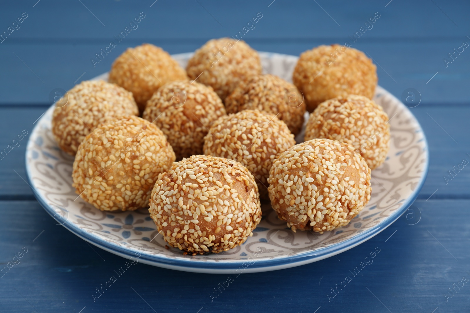Photo of Delicious sesame balls on blue wooden table, closeup