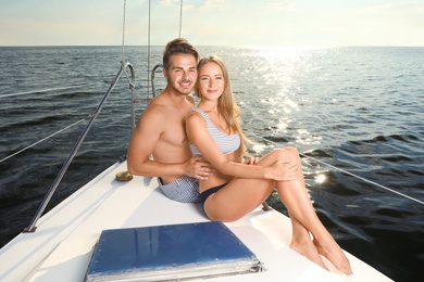 Photo of Young man and his beautiful girlfriend in bikini sitting on yacht. Happy couple on vacation