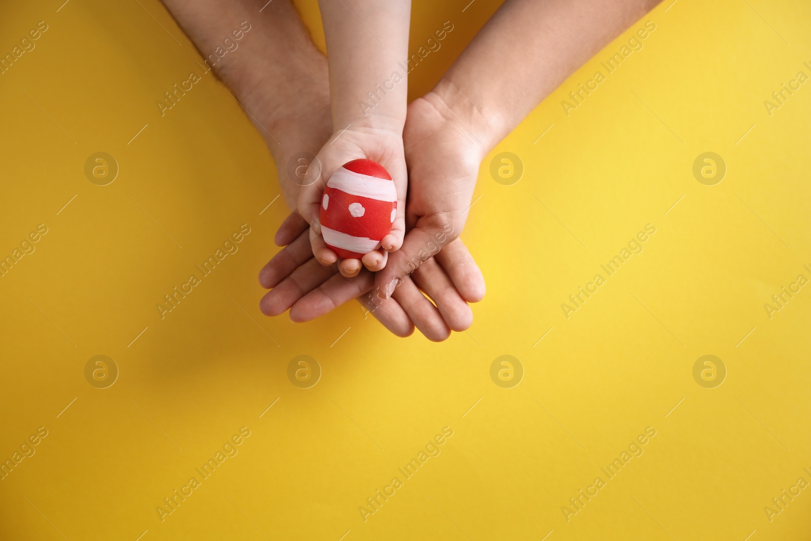 Photo of Father, mother and their child holding painted Easter egg on color background, top view. Space for text