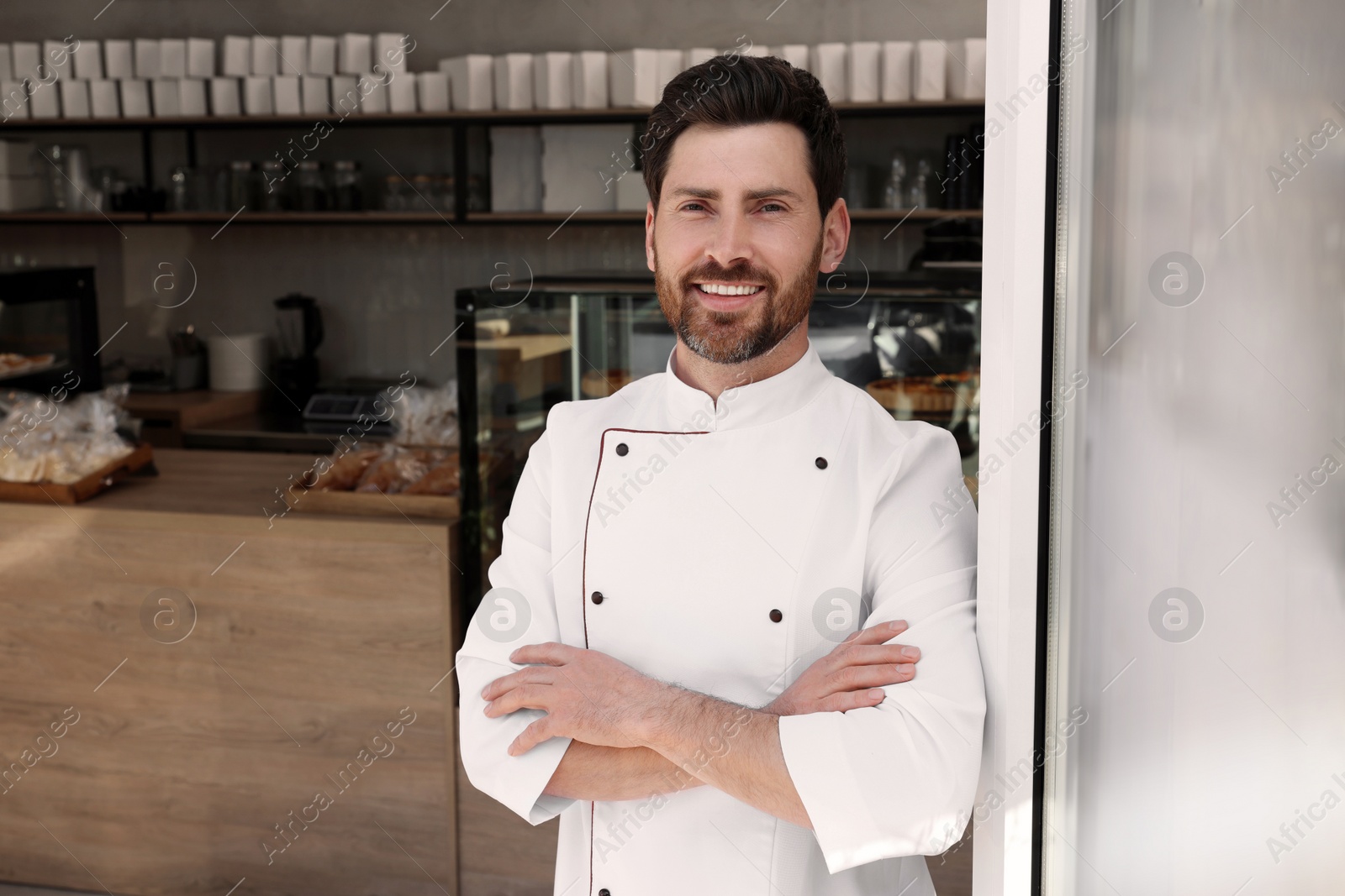 Photo of Portrait of professional baker in bakery shop. Space for text