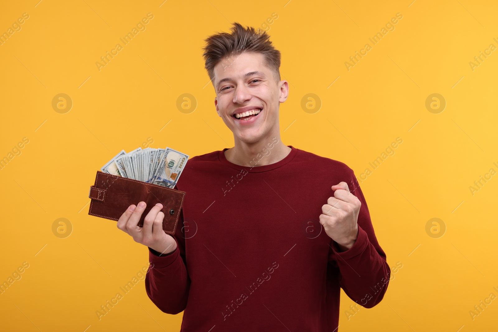 Photo of Happy man with money and wallet on yellow background