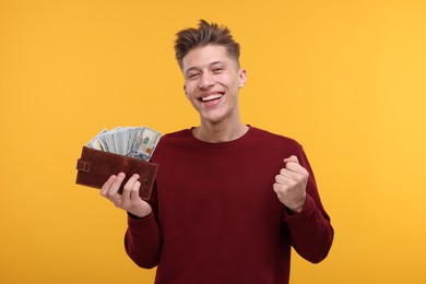 Photo of Happy man with money and wallet on yellow background