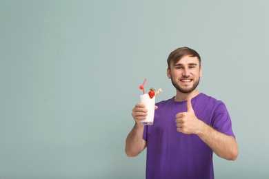 Photo of Young man with glass of delicious milk shake on color background