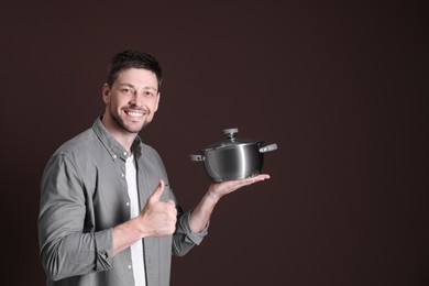 Photo of Happy man with pot on dark background. Space for text