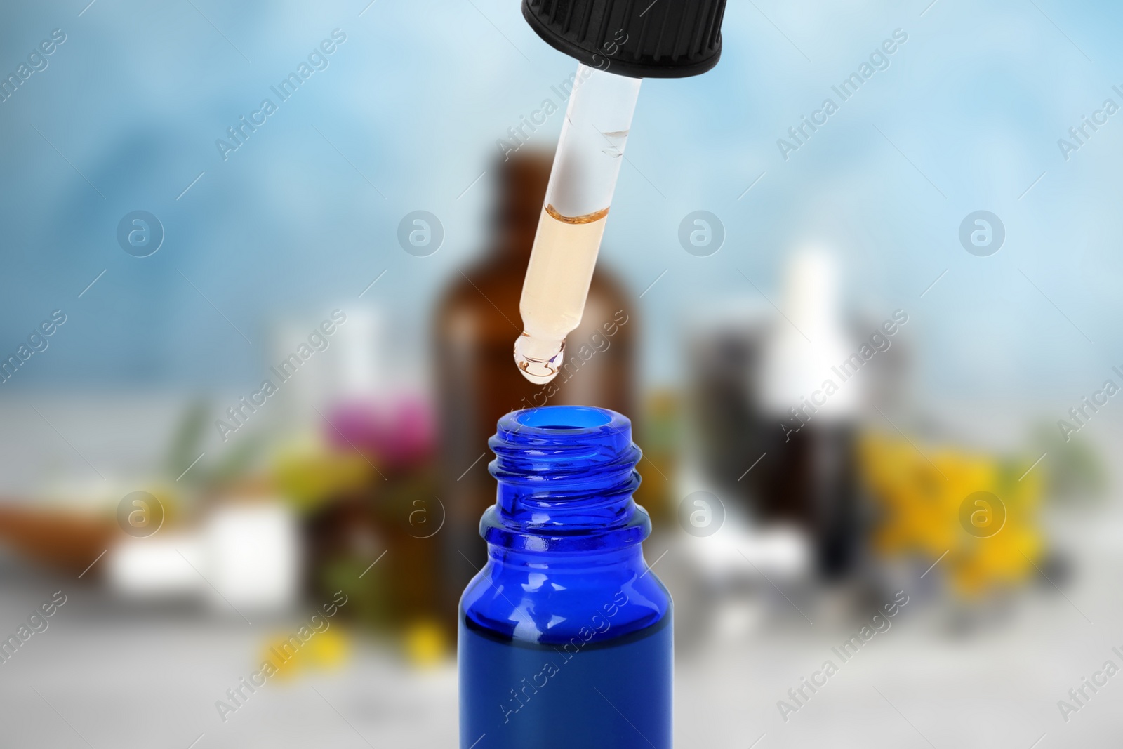 Image of Little bottle with essential oil and dropper against blurred background 