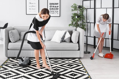 Professional chambermaids cleaning floor in hotel room