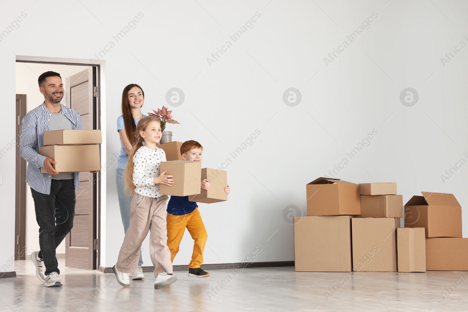 Photo of Happy family with moving boxes entering in new apartment. Settling into home