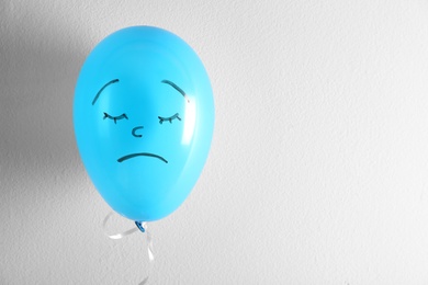 Photo of Air balloon with drawn sad face on white background. Space for text