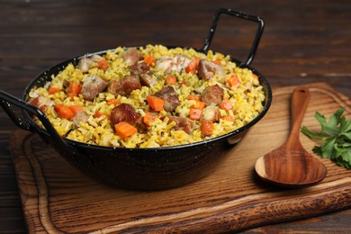 Photo of Delicious pilaf with meat, carrot and garlic served on wooden table