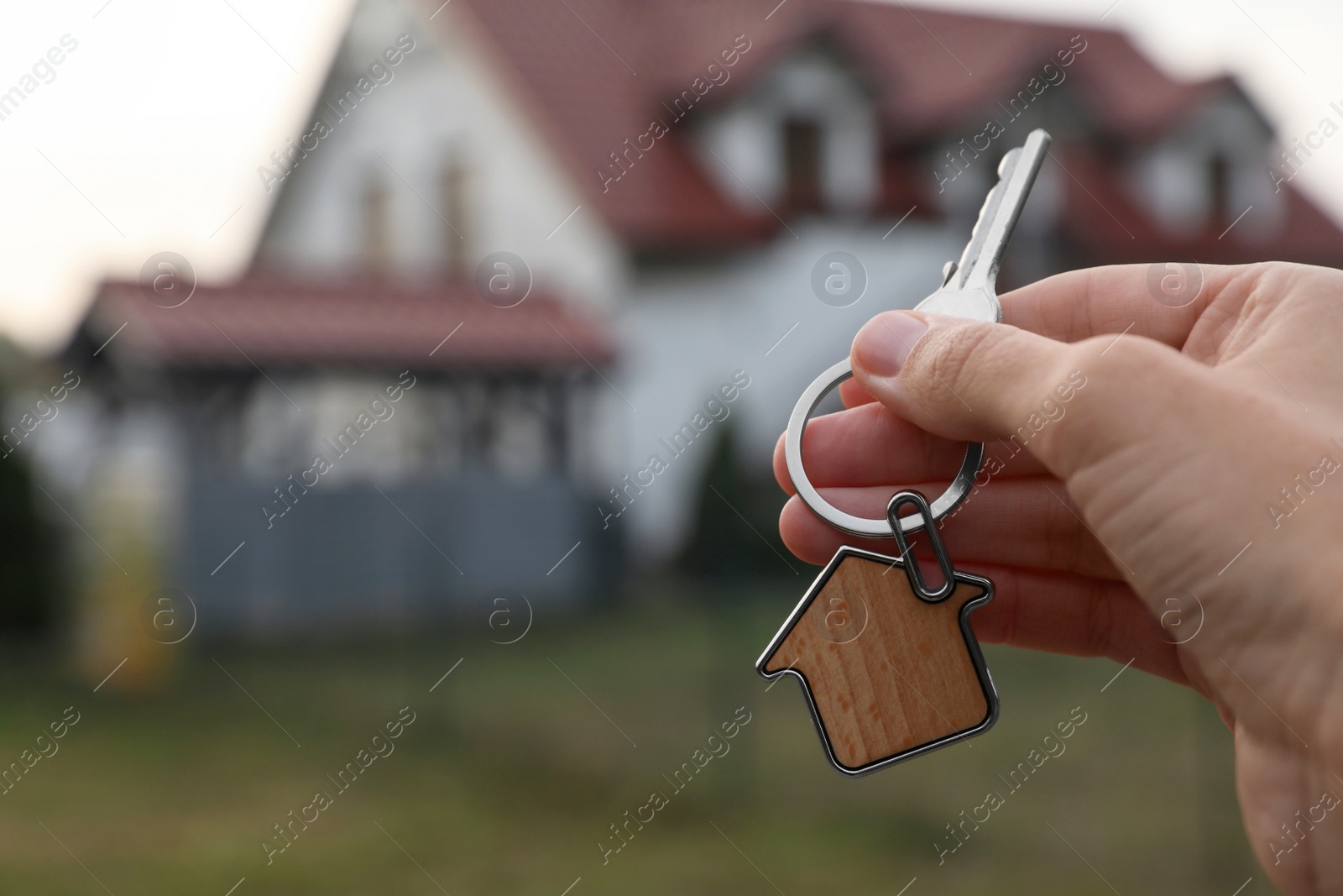 Photo of Woman holding house keys outdoors, closeup with space for text. Real estate agent