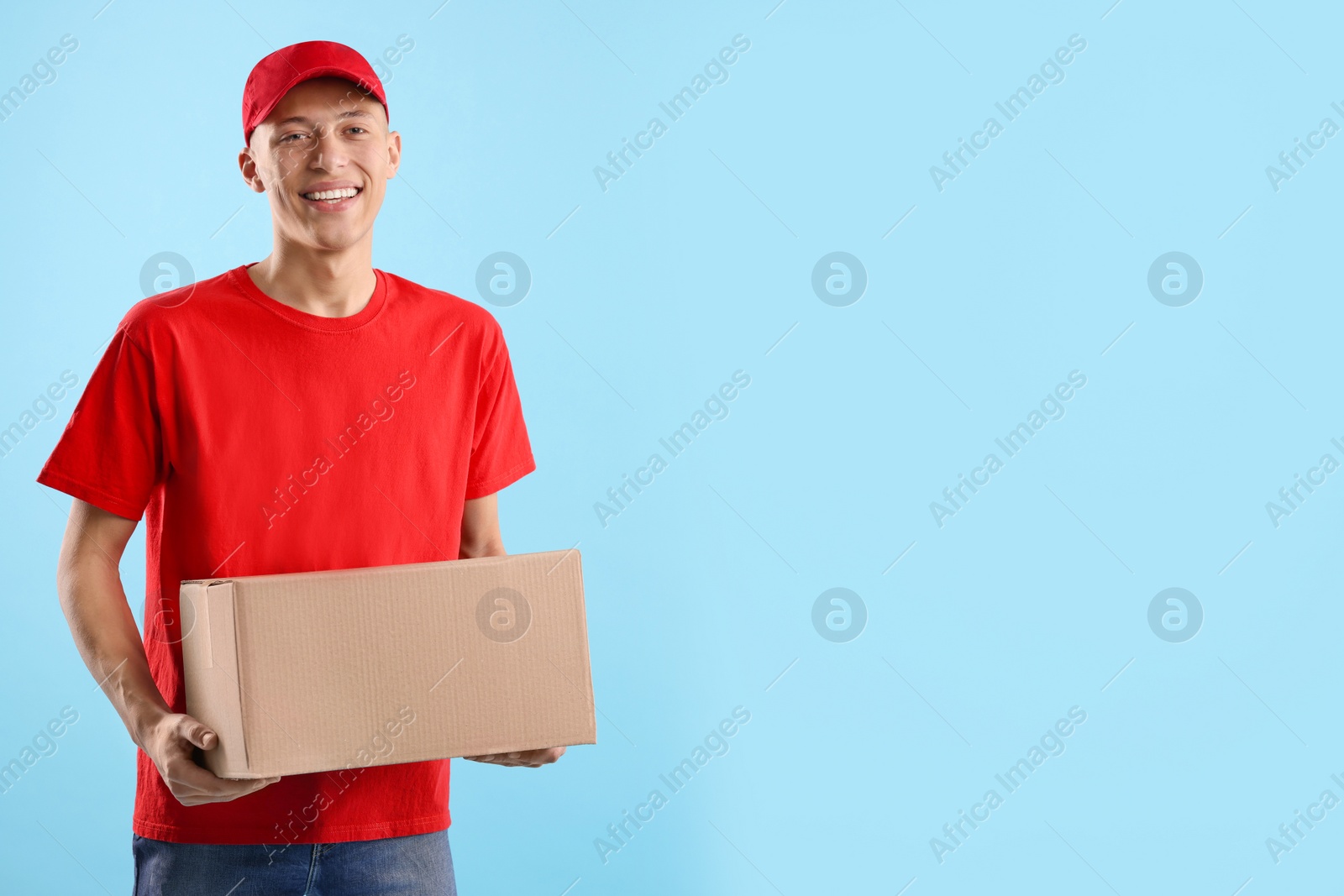 Photo of Happy courier with parcel on light blue background. Space for text