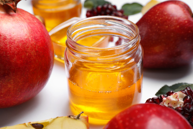 Photo of Honey, apples and pomegranate on white background, closeup. Rosh Hashanah holiday