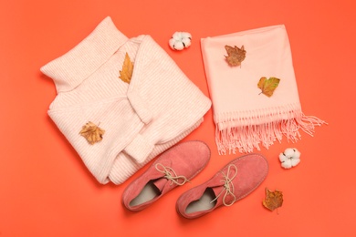 Flat lay composition with sweater and dry leaves on orange background. Autumn season
