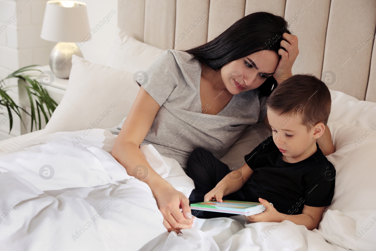 Photo of Depressed single mother with child in bed at home