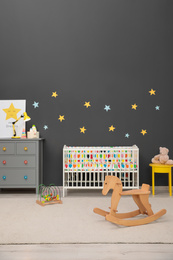 Cute baby room interior with modern crib and rocking horse