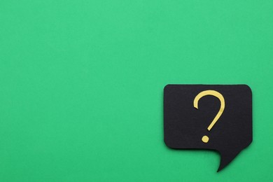 Photo of Paper speech bubble with question mark on green background, top view. Space for text