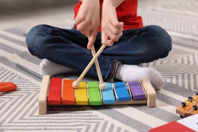 Photo of Little boy playing toy xylophone at home, closeup