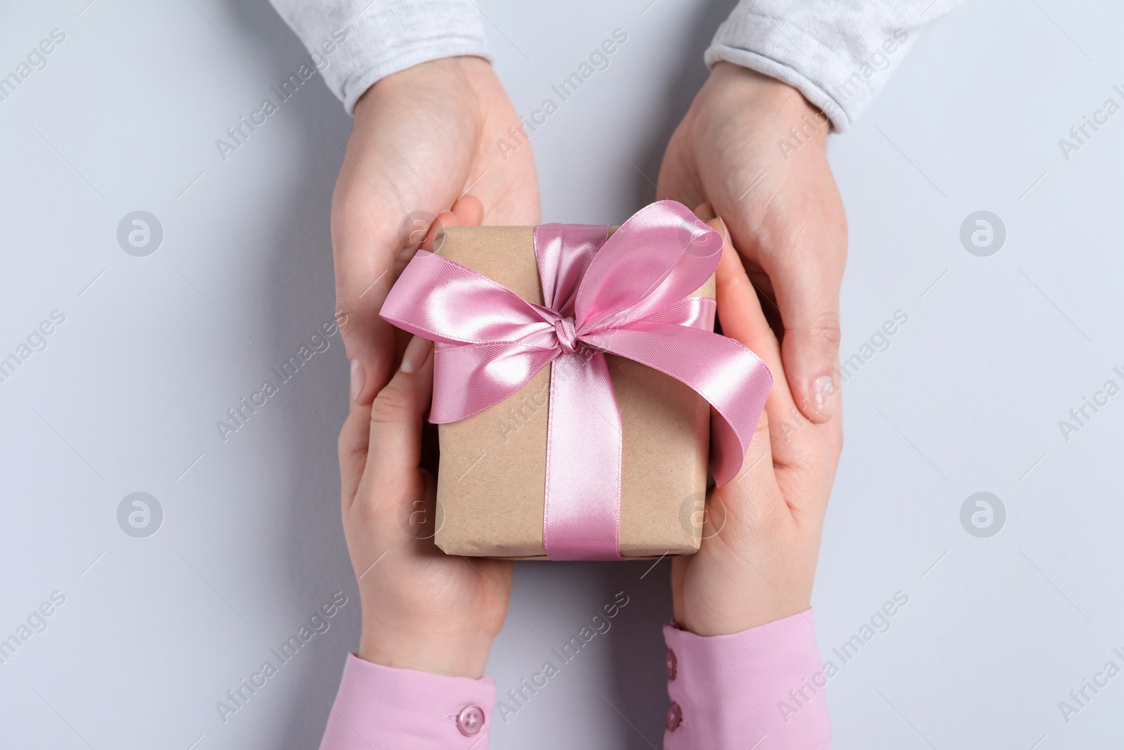 Photo of Man giving gift box to woman on light gray background, top view