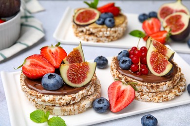 Photo of Tasty crispbreads with chocolate, figs and berries served on light table