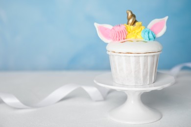 Photo of Dessert stand with cute sweet unicorn cupcakes on white table. Space for text