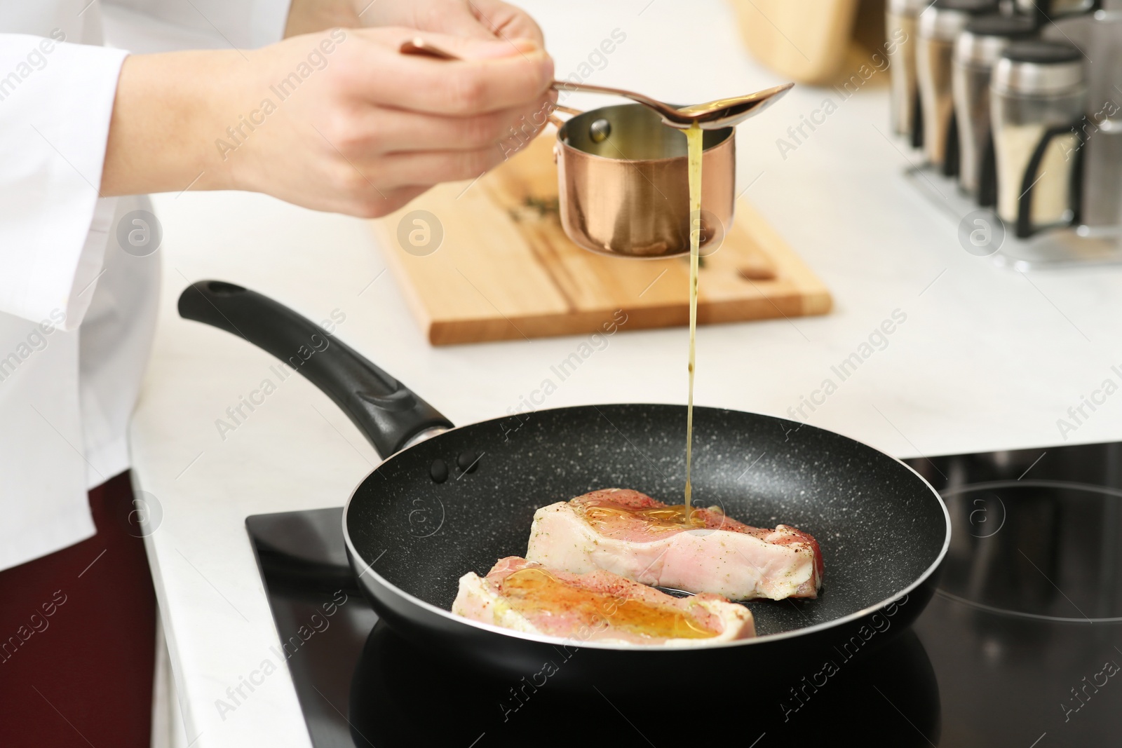 Photo of Professional chef pouring sauce into frying pan in kitchen, closeup