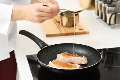 Professional chef pouring sauce into frying pan in kitchen, closeup