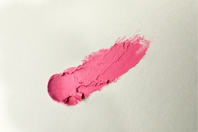 Smear of beautiful lipstick on beige background, top view