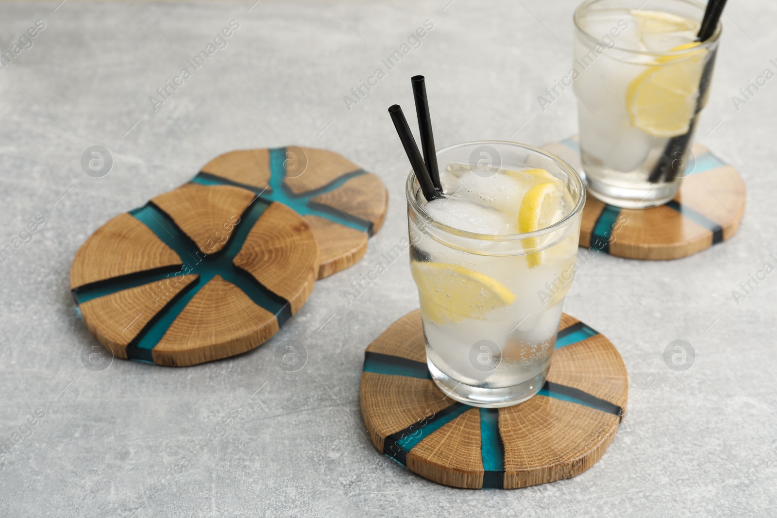 Photo of Cocktail and stylish cup wooden coasters on light grey table