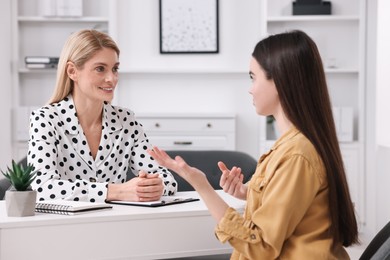 Photo of Psychologist working with teenage girl at table in office