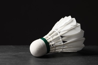 Photo of Feather badminton shuttlecock on grey table against black background, closeup. Space for text