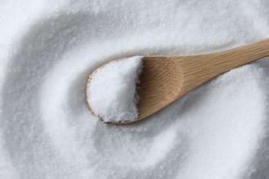 Photo of Wooden spoon on white sea salt, top view